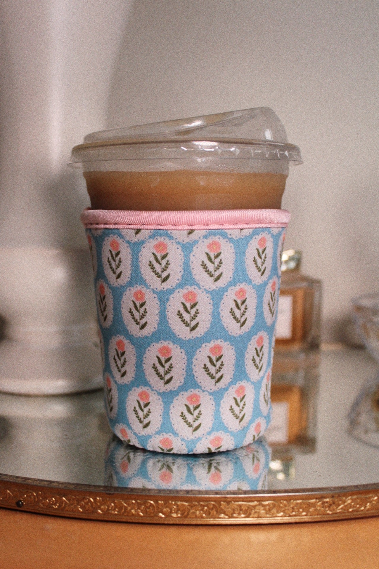 Blue coffee sleeve with a pink band and a vintage pink flowered patterned design
